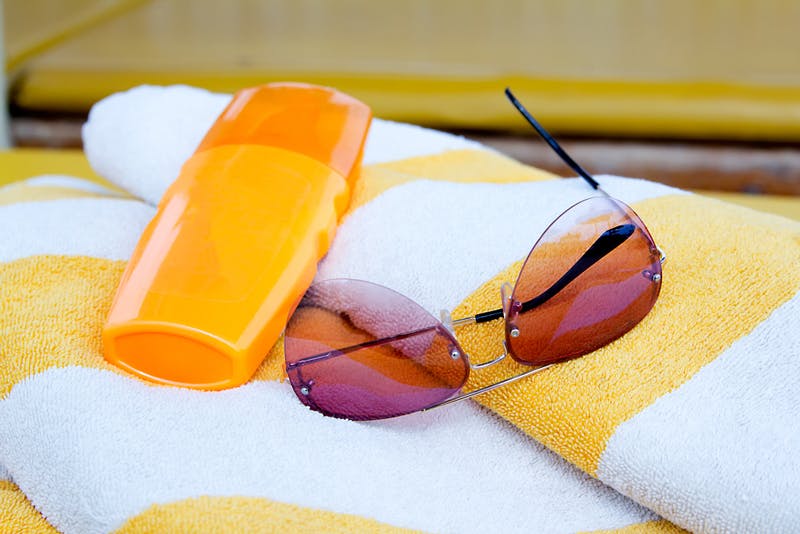 sun tan lotion and sunglasses on a beach towel