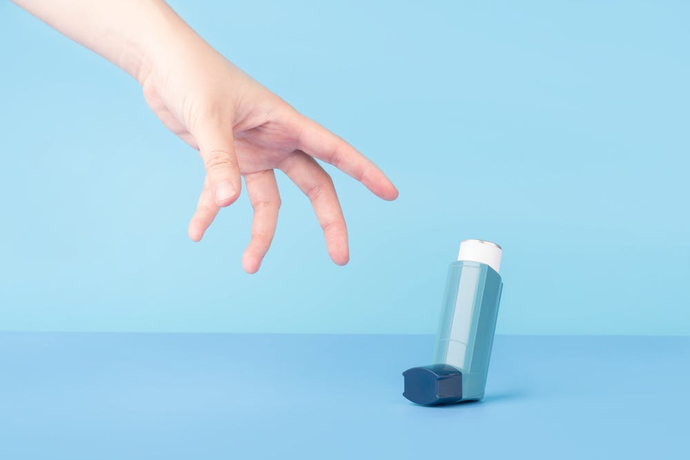 A hand reaching for a Ventolin inhaler