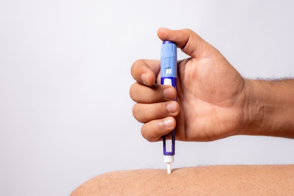 A weight loss pen being self administered in a person's thigh