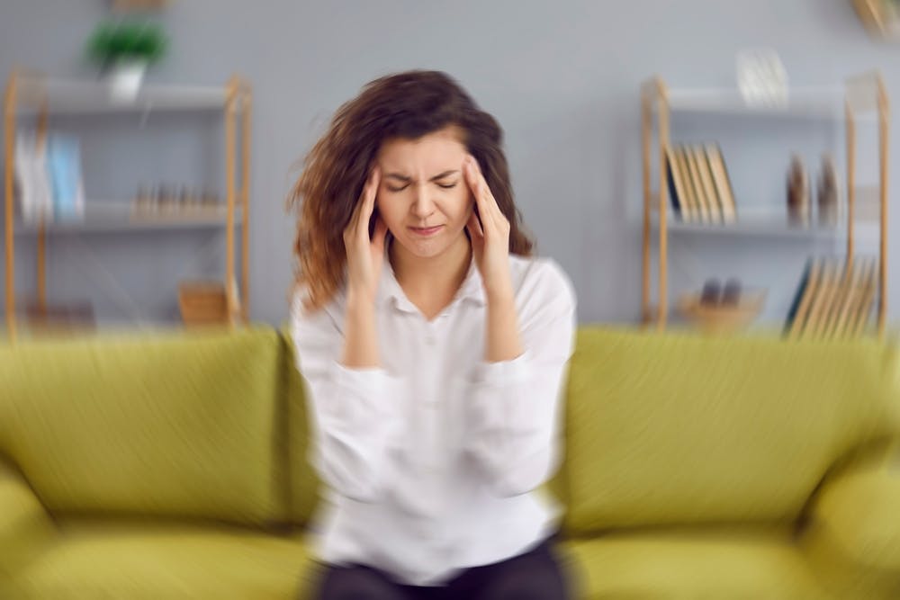 A lady experiencing a migraine whilst sat on a sofa