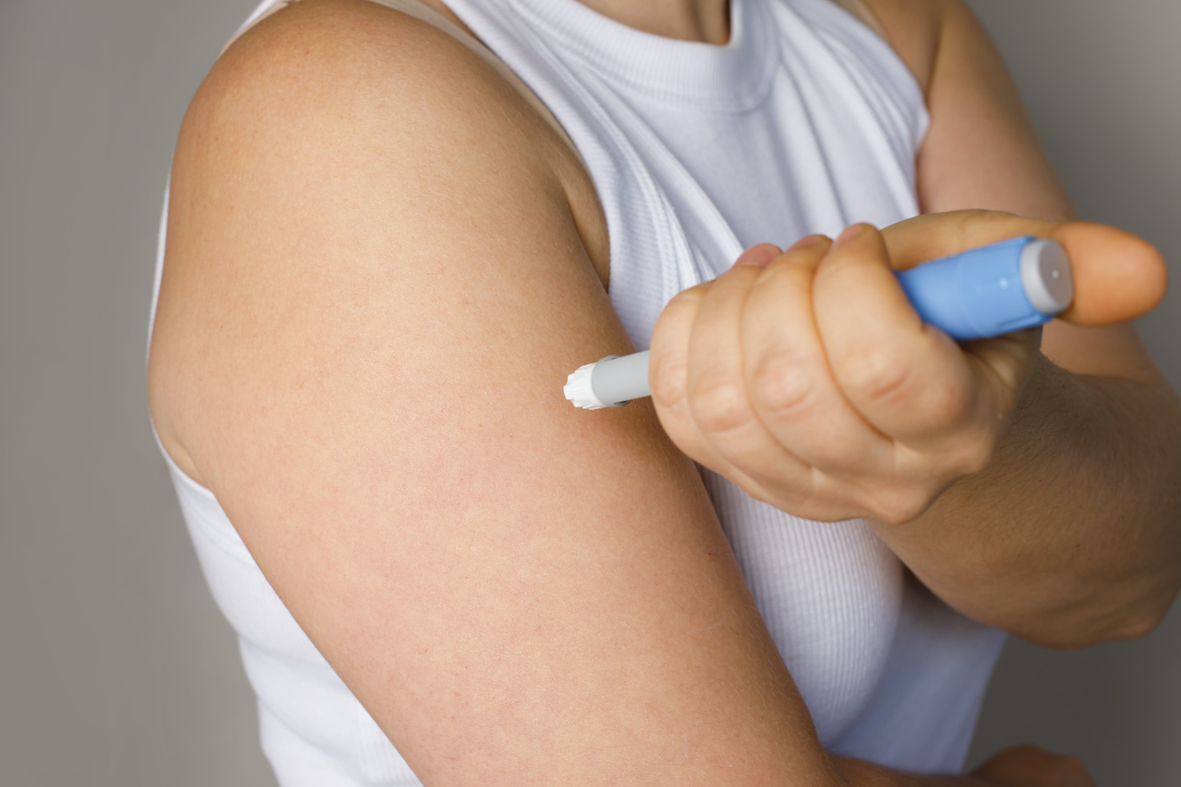 An Ozempic pen injection being self administered into an arm