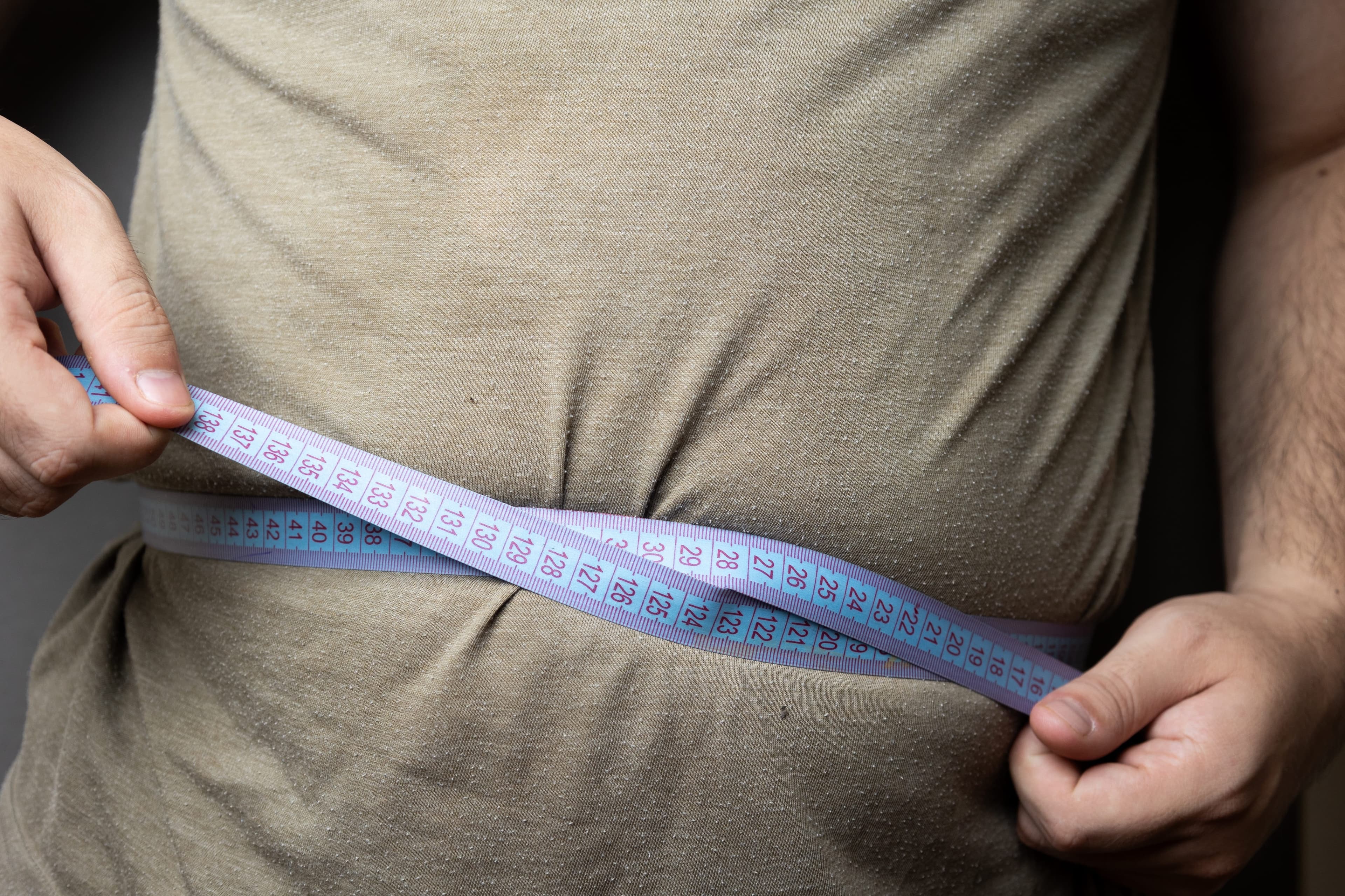 A tape measure being wrapped around a stomach to measure it