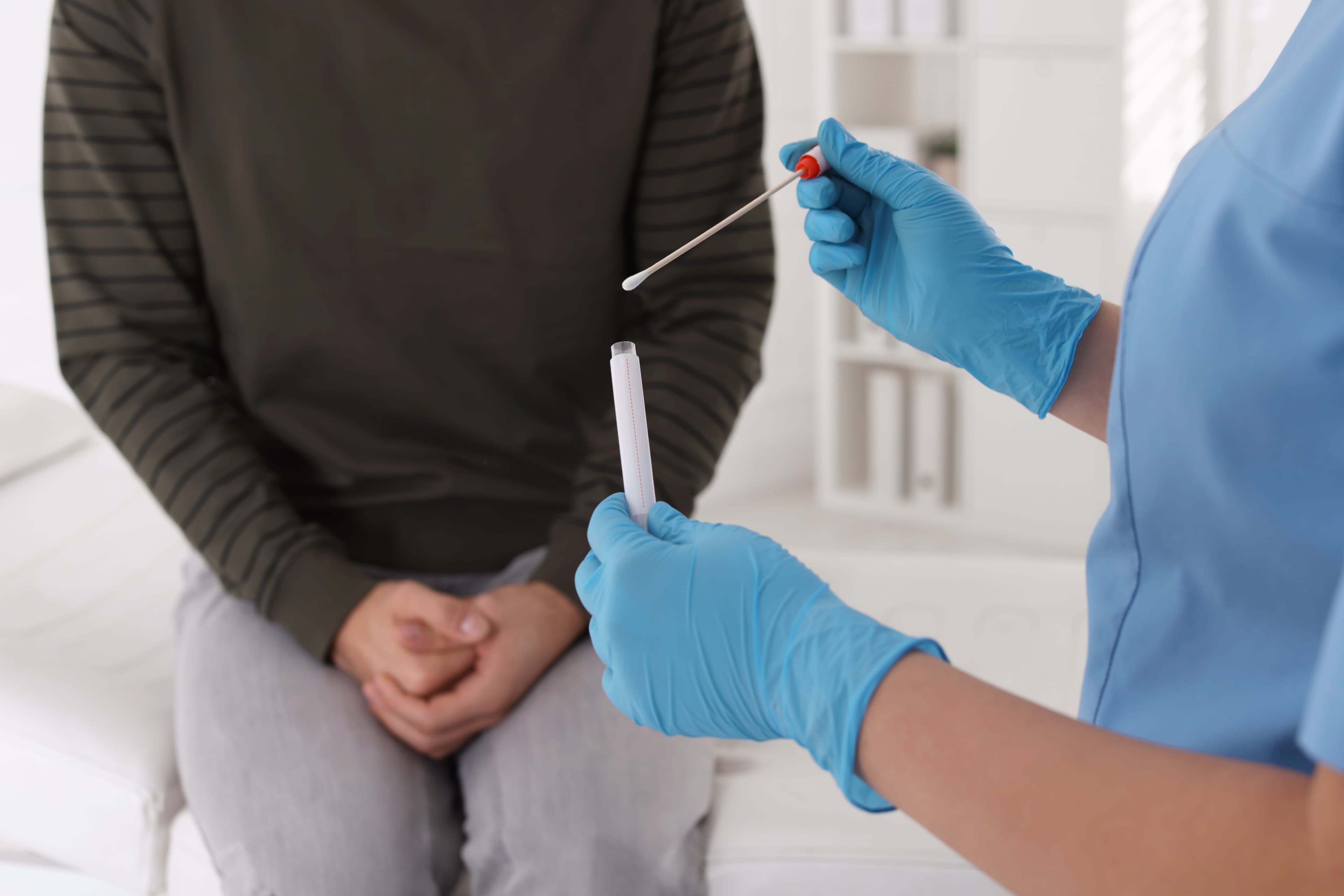 A medical professional taking a swab sample from a patient to check for genital herpes