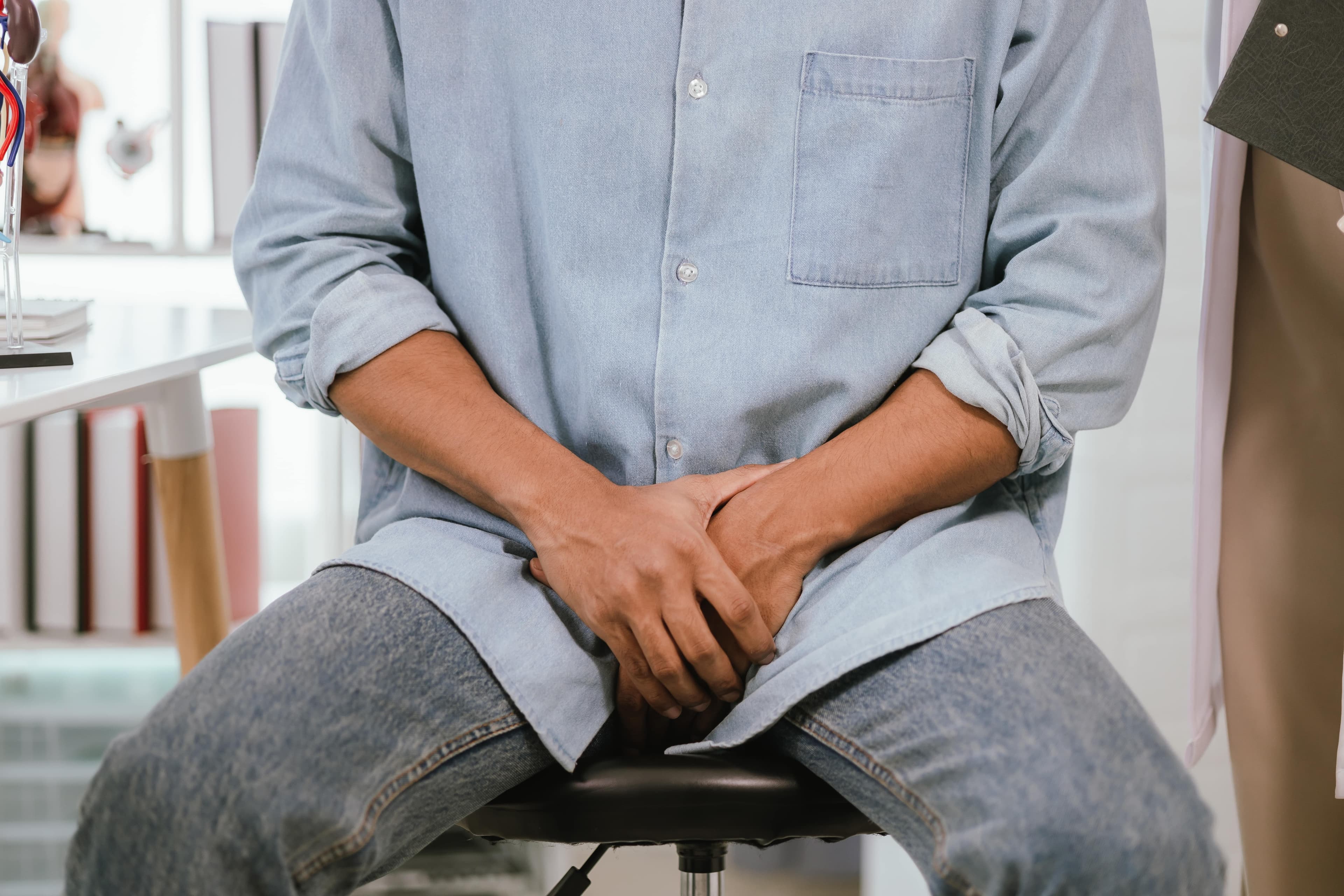 A man sat down with his hands covering his crotch