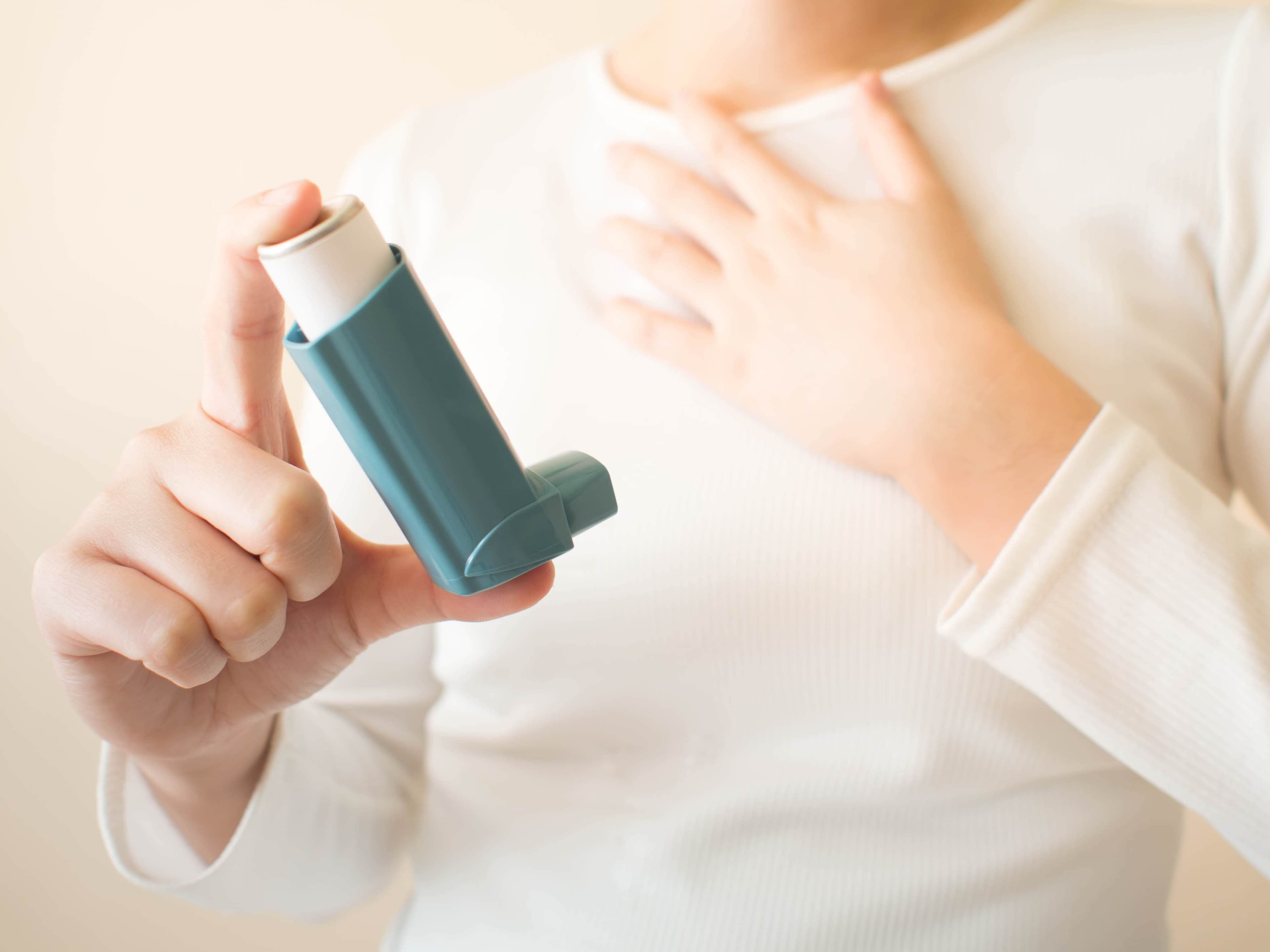 A hand holding up a Ventolin (salbutamol) inhaler