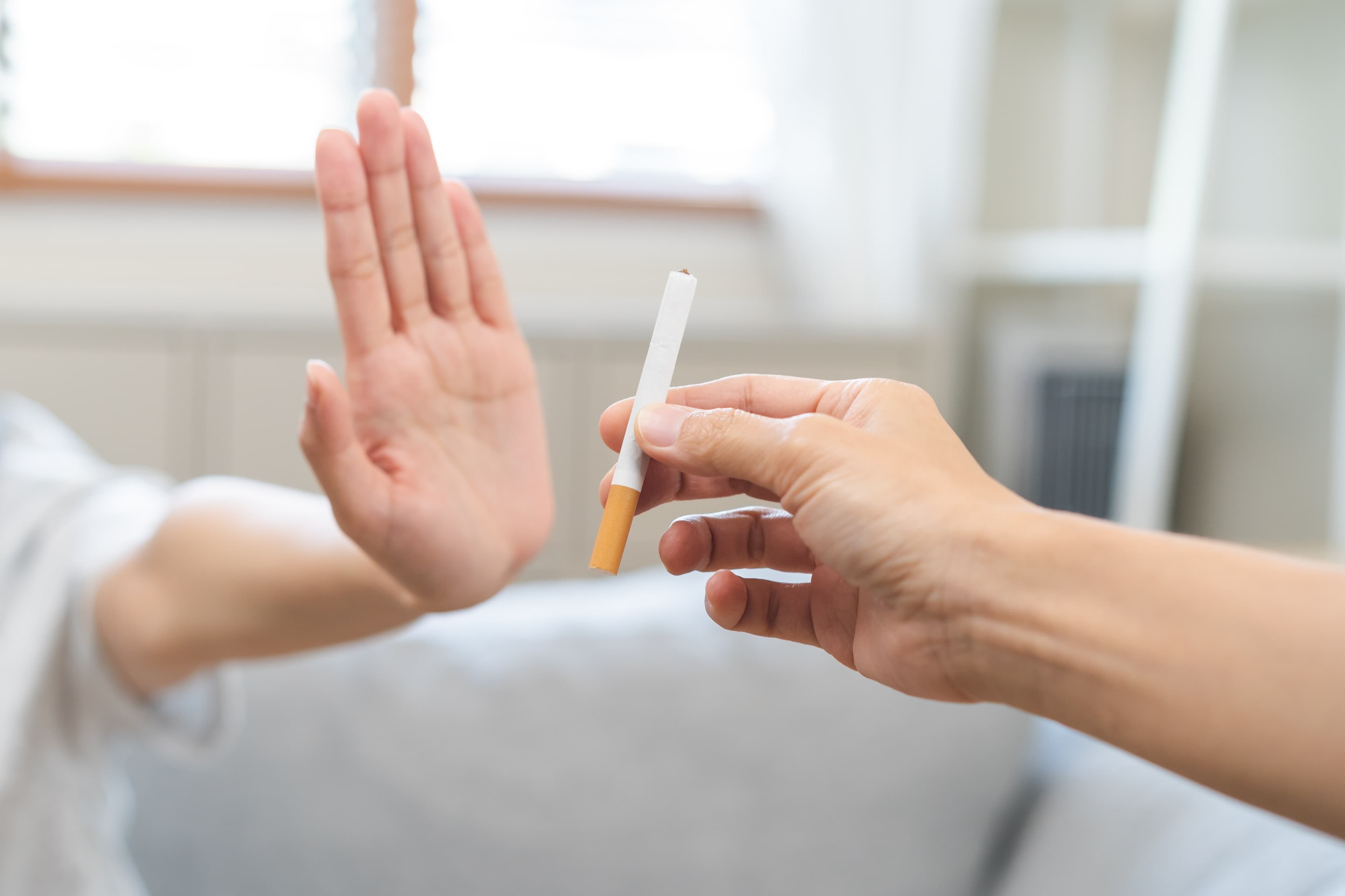 A person's hand rejecting a cigarette